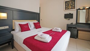 A hotel room with a neatly made bed, a bedside table, a desk with a mirror, and a television. - Ömer Aybak Beach Hotel (Bodrum)