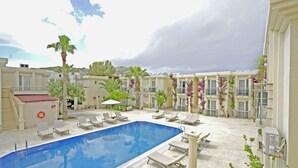 A swimming pool with lounge chairs, a lifebuoy, and a palm tree. - Ömer Aybak Beach Hotel (Bodrum)