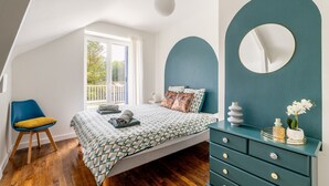 A bedroom with a bed, a dresser, a chair, and a large window.