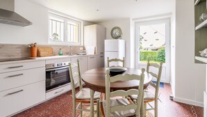 A kitchen with white cabinetry, a stove, and a dining table with chairs.