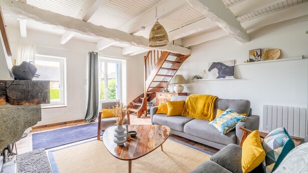A spacious living room with a grey sofa, wooden coffee table, and a staircase leading to an upper level.