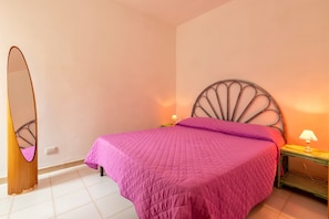 A bedroom with a bed, a nightstand, a lamp, and a mirror.