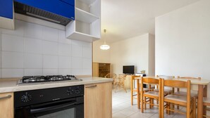 Une cuisine moderne équipée d’une cuisinière à gaz, d’un four et de meubles de rangement en bois. On y trouve également un coin repas avec une table et des chaises.