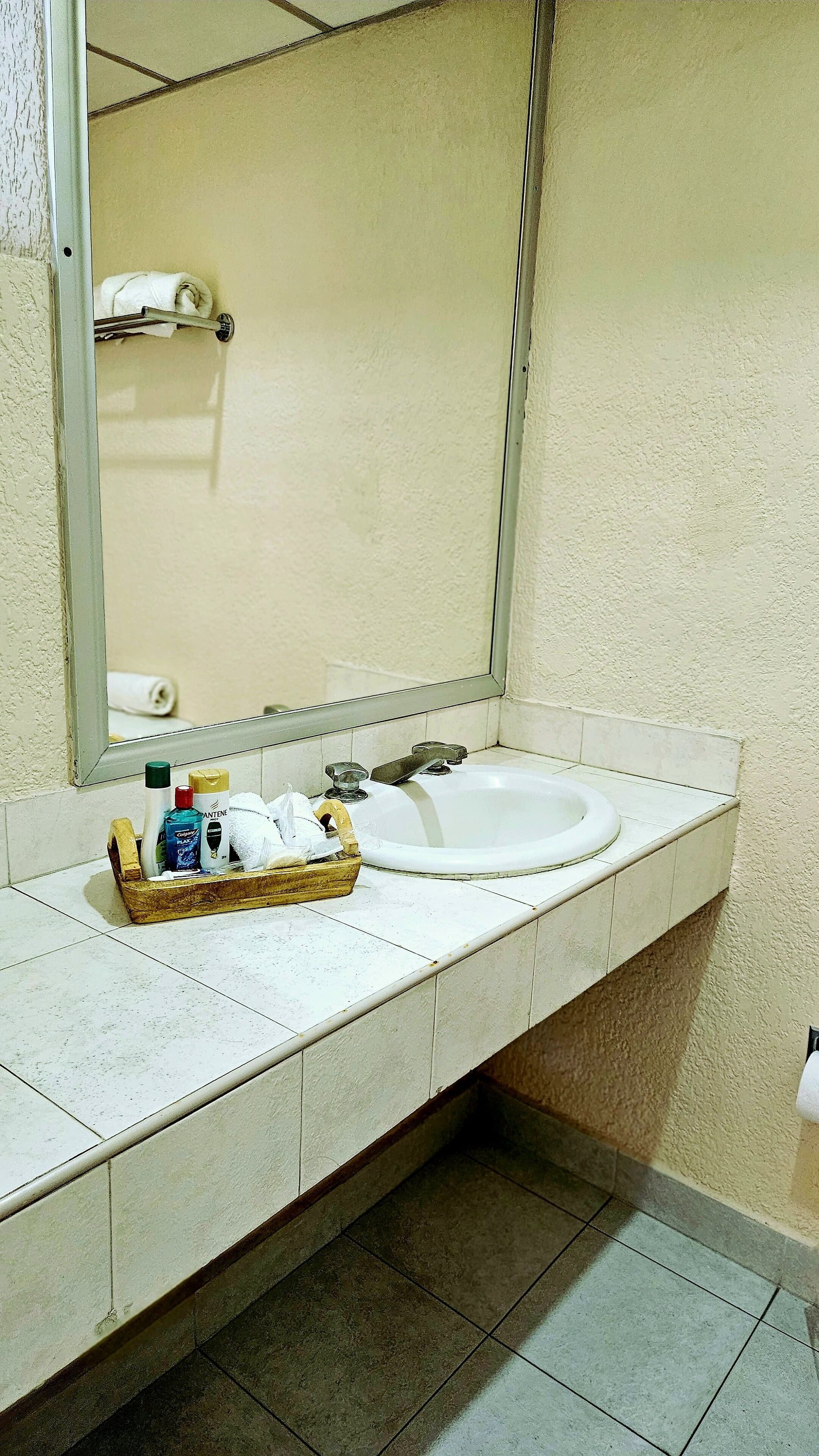 Un baño con lavamanos blanco, espejo y barra para toallas.