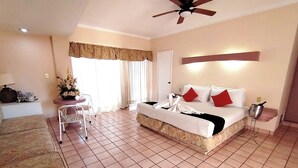 A hotel room with a bed, a desk, a chair, a potted plant, and a ceiling fan. - HOTEL HACIENDA DEL RIO (Yautepec)