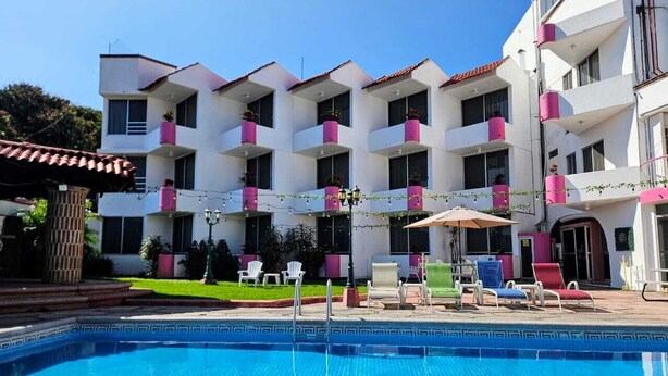 A hotel with a swimming pool, outdoor seating, and balconies with potted plants. - HOTEL HACIENDA DEL RIO (Yautepec)
