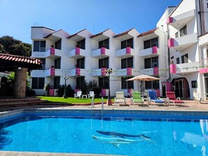 A hotel with a swimming pool, outdoor seating, and balconies with potted plants. - HOTEL HACIENDA DEL RIO (Yautepec)