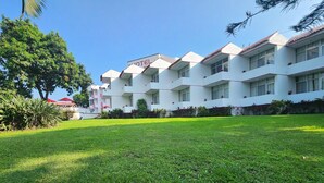 A hotel with a white exterior, multiple balconies, and a well-maintained lawn. - HOTEL HACIENDA DEL RIO (Yautepec)