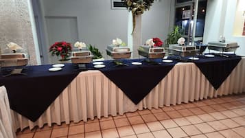 Una taula de buffet amb diverses zones de servei, tovallons blancs i un sòl de rajola.