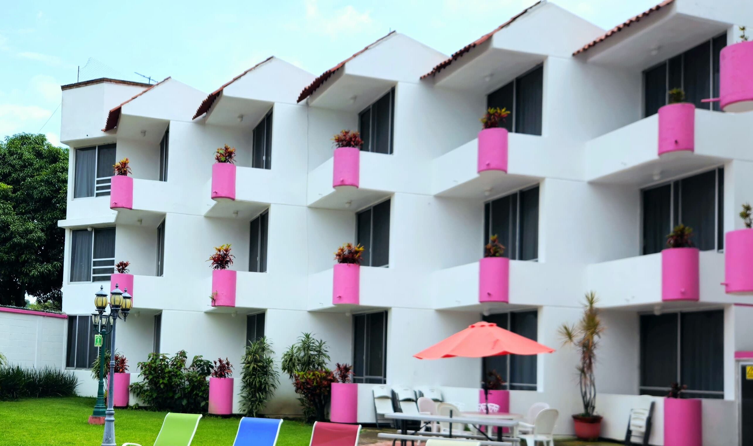 A multi-story building with balconies, outdoor seating, and potted plants.