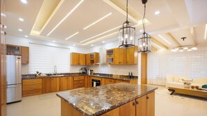 A modern kitchen with wooden cabinets, a granite countertop, and pendant lighting. - Hermosa villa rodeada de montañas, Combina elegancia moderna con la naturaleza. (Bonao)