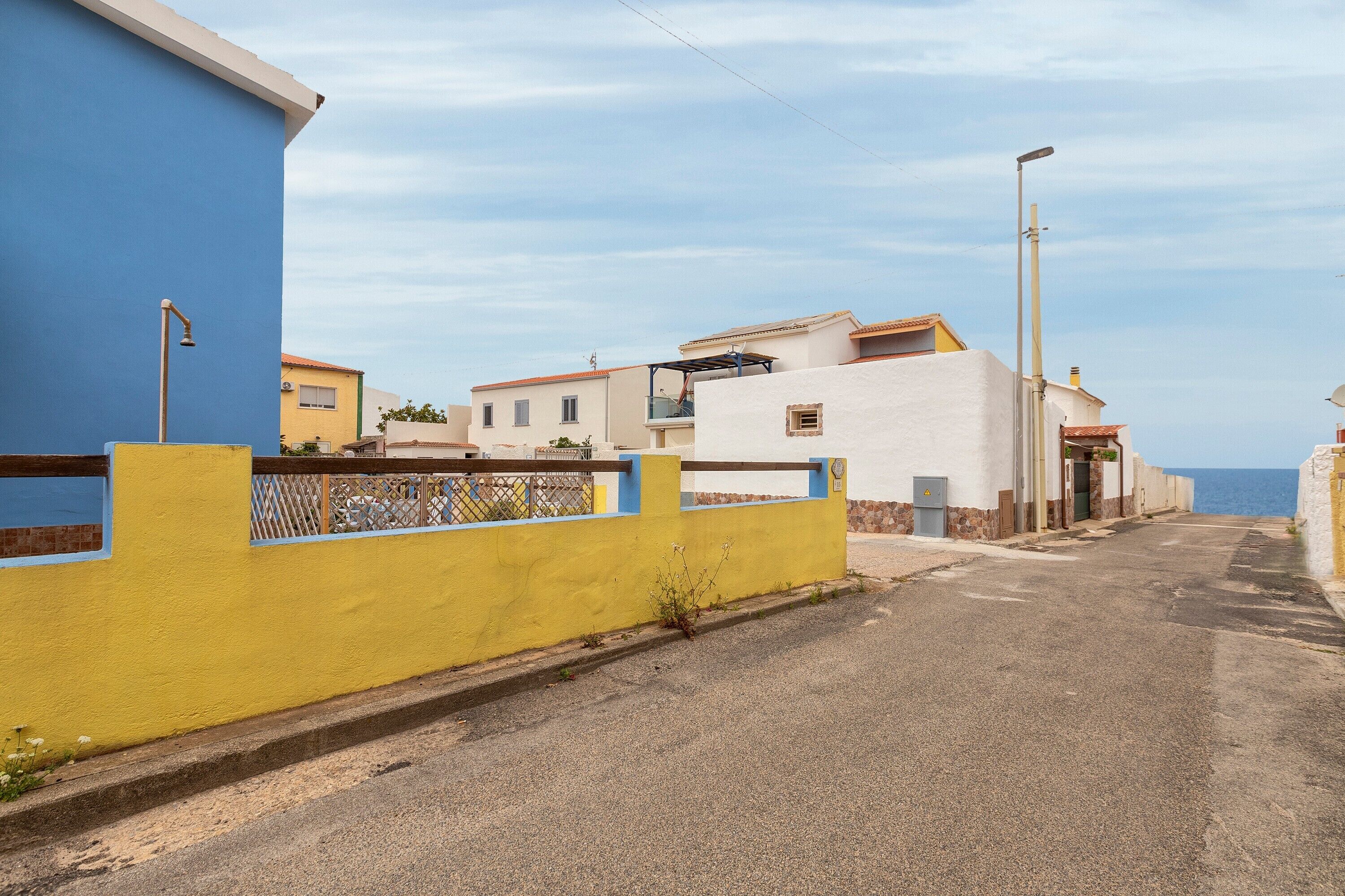 A residential street with houses, a clear sky, and a view of the sea.