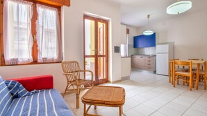 Une pièce comprenant un lit, une table à manger avec des chaises, un coin cuisine et une porte donnant sur l’extérieur.