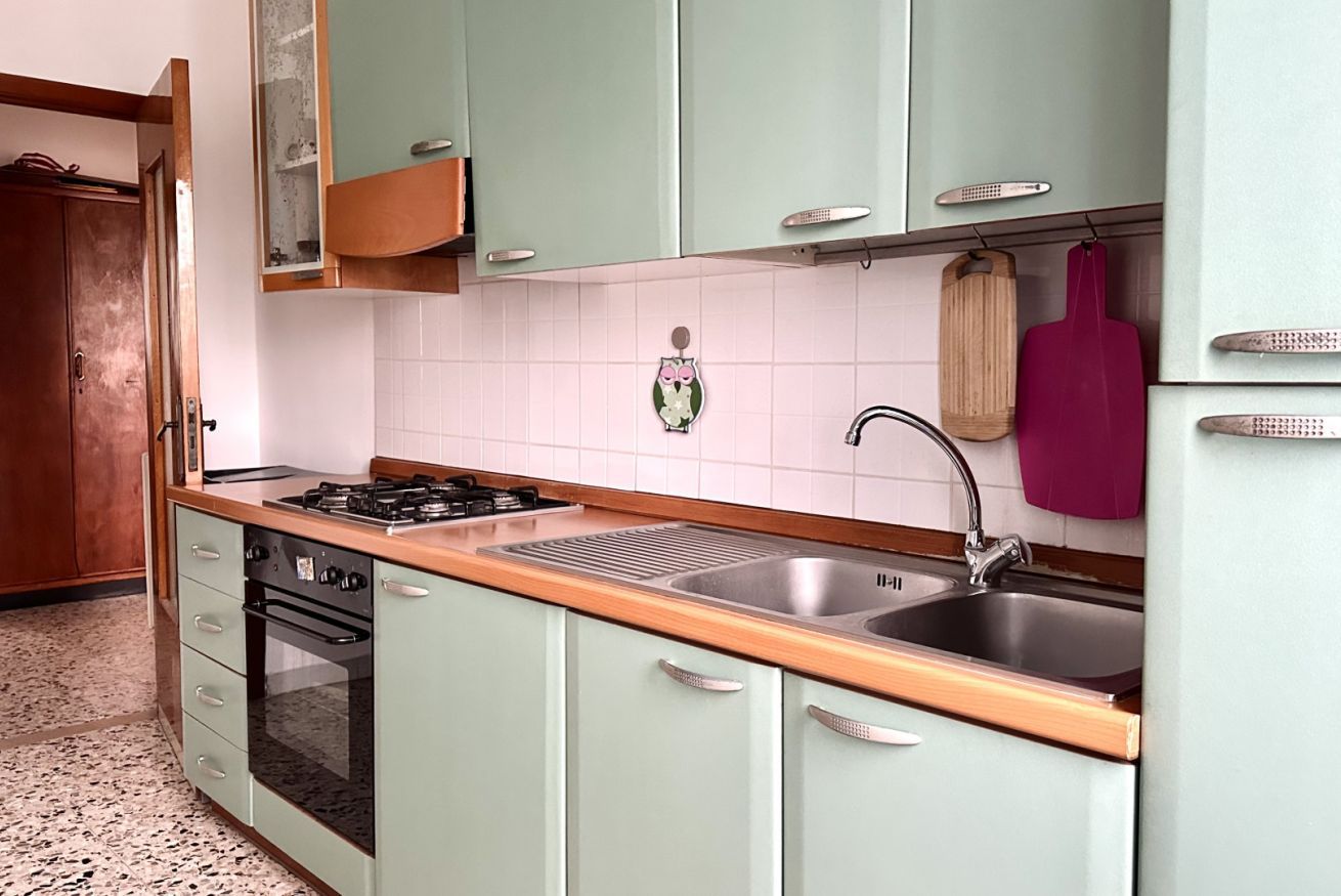 Cucina con piano cottura a gas, forno, lavello e pensili.