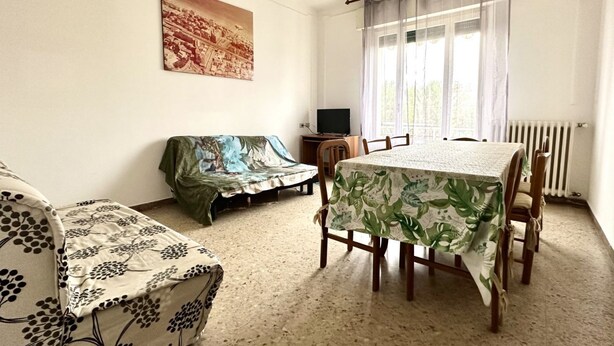 Una habitación con una mesa de comedor, un sofá, un televisor y un radiador.