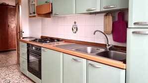 Una cocina con estufa a gas, horno, pileta y alacenas.