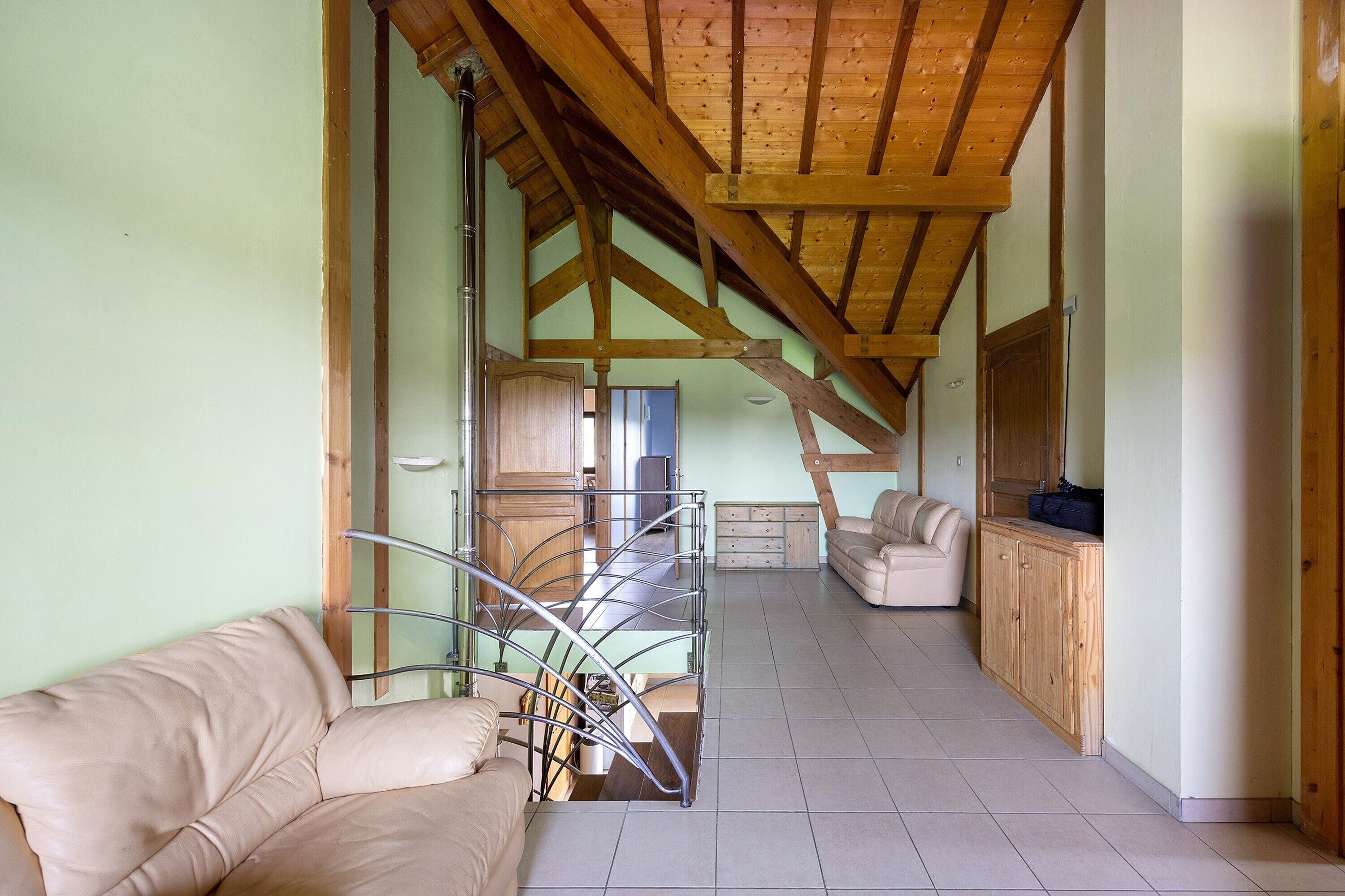 Una habitación amplia con techo alto, una escalera, un sofá y un armario.