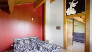 A bedroom with a bed, a wooden ceiling, a red wall, and a door leading to another room. - Cottage 'Villa De St Off' with Mountain View, Private Terrace and Wi-Fi (Saint-Offenge)