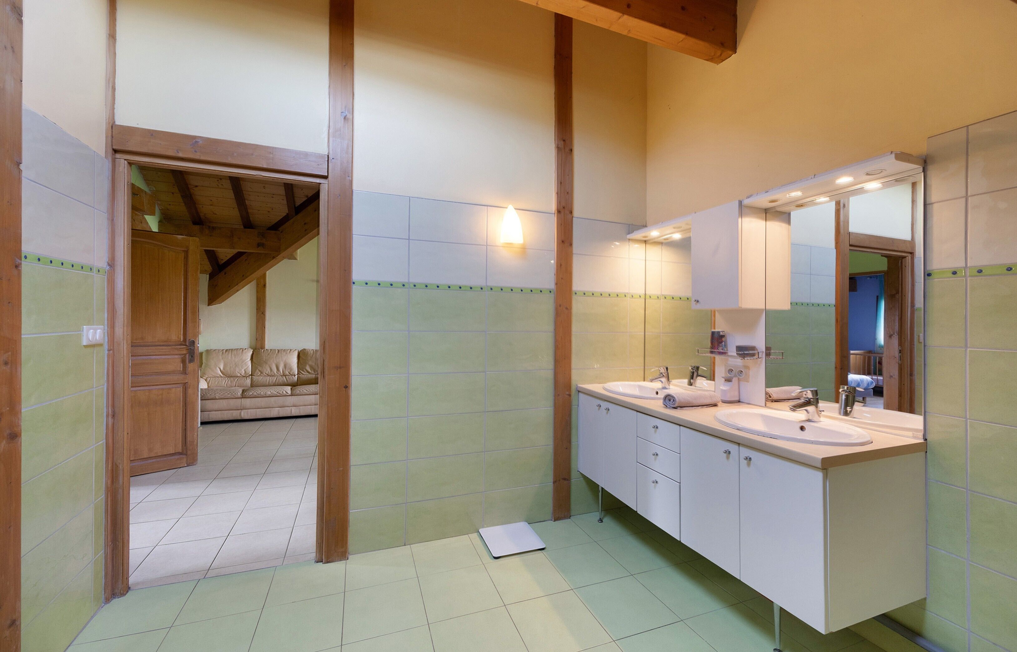 Un baño con un espejo grande, dos lavamanos y techo de madera.