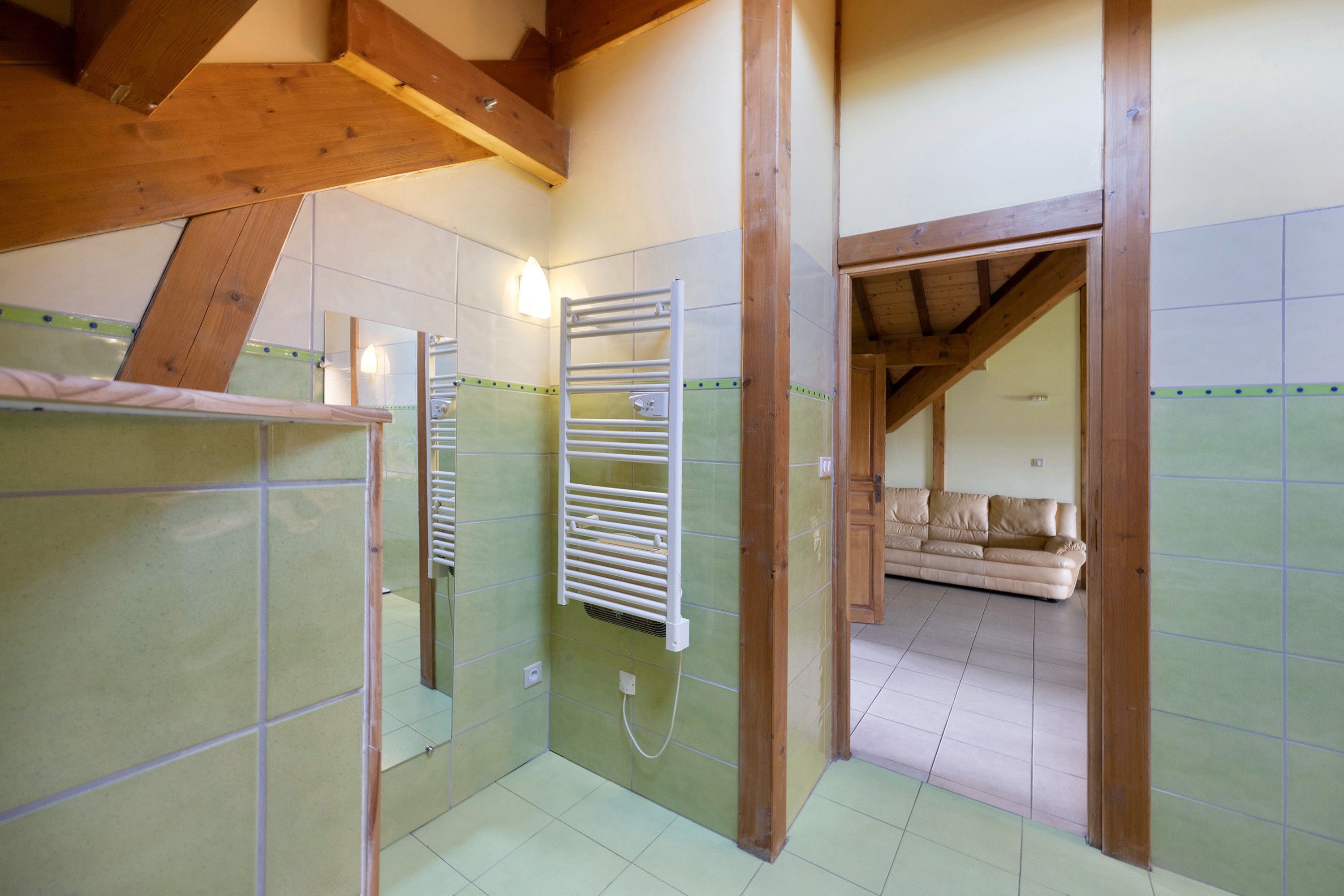 A bathroom with a shower, a towel rack, and a mirror.