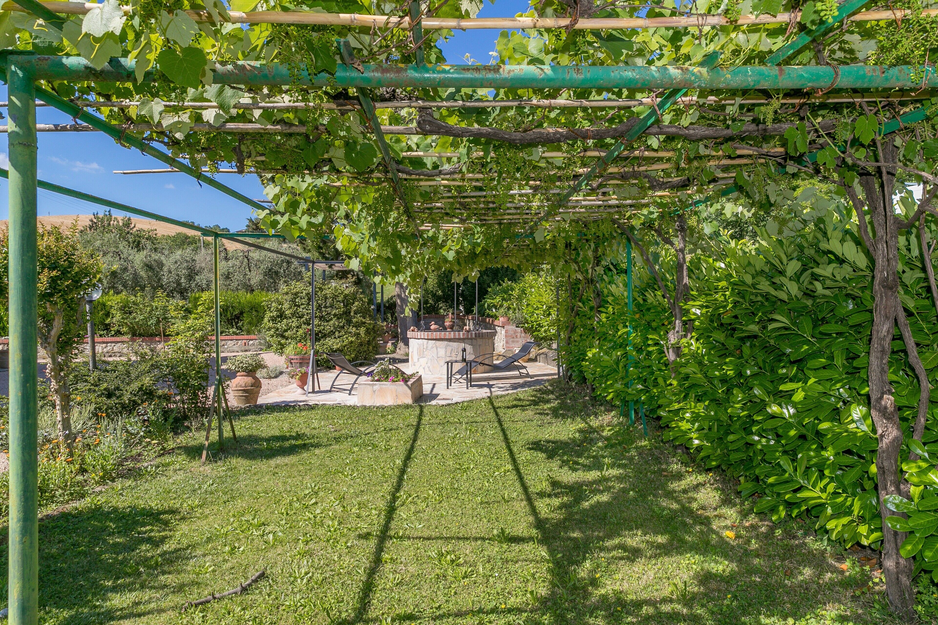 Un jardin agrémenté d’une pergola, d’un espace détente et offrant une vue sur le paysage environnant.
