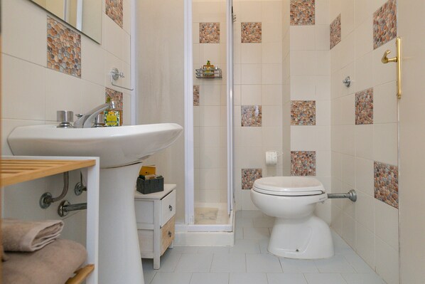 Un baño con lavabo, inodoro, ducha y toallero.