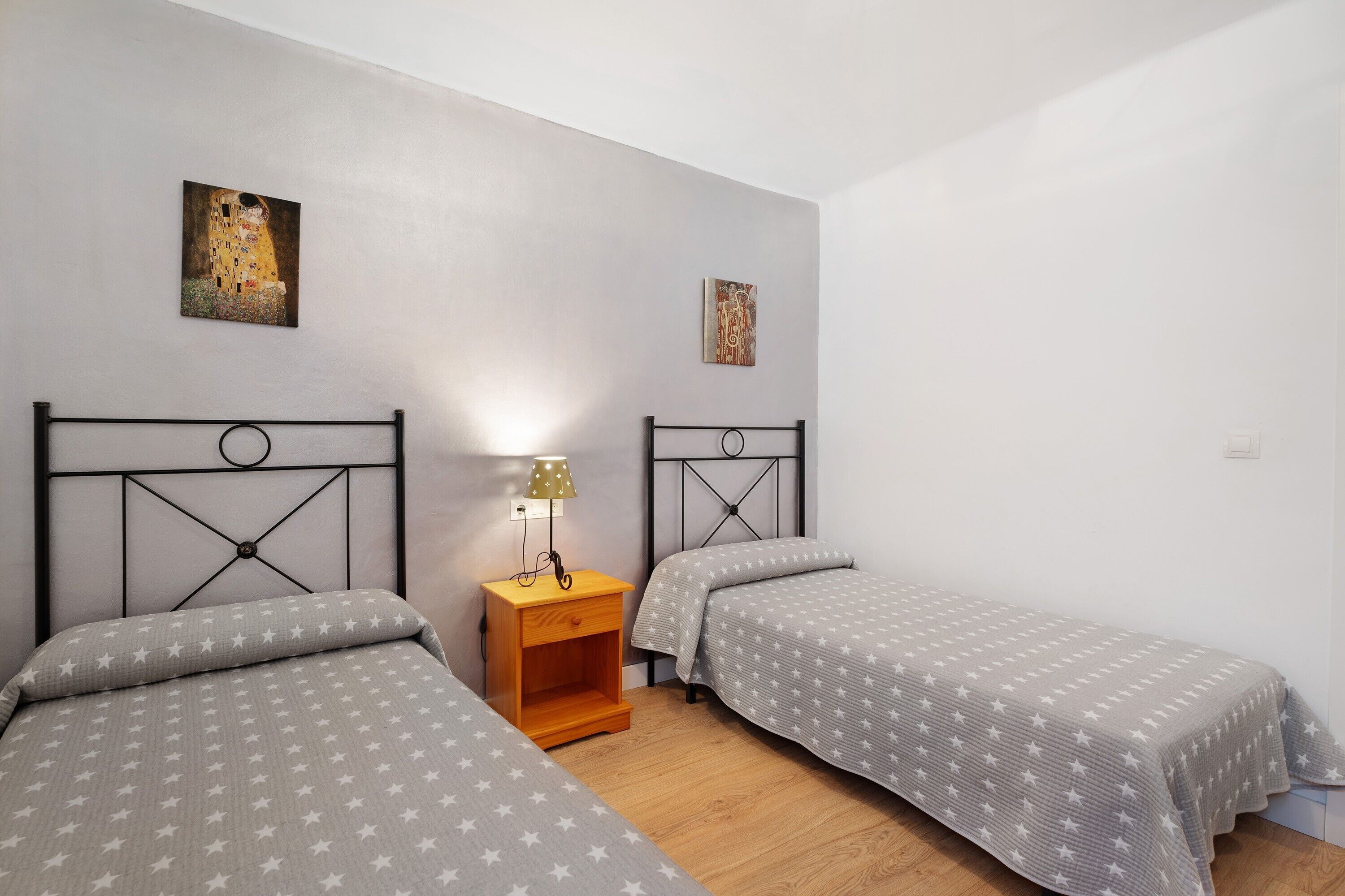 Un dormitorio con dos camas, una mesita de noche y decoración en la pared.