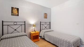 Un dormitorio con dos camas, una mesita de noche y decoración en la pared.