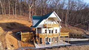 Ein zweistöckiges Haus mit grüner Dachbegrünung, einer Holzterrasse und einem Steinfundament.