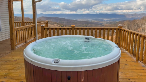 Ein Whirlpool auf einer Holzterrasse mit Blick auf die Berge.