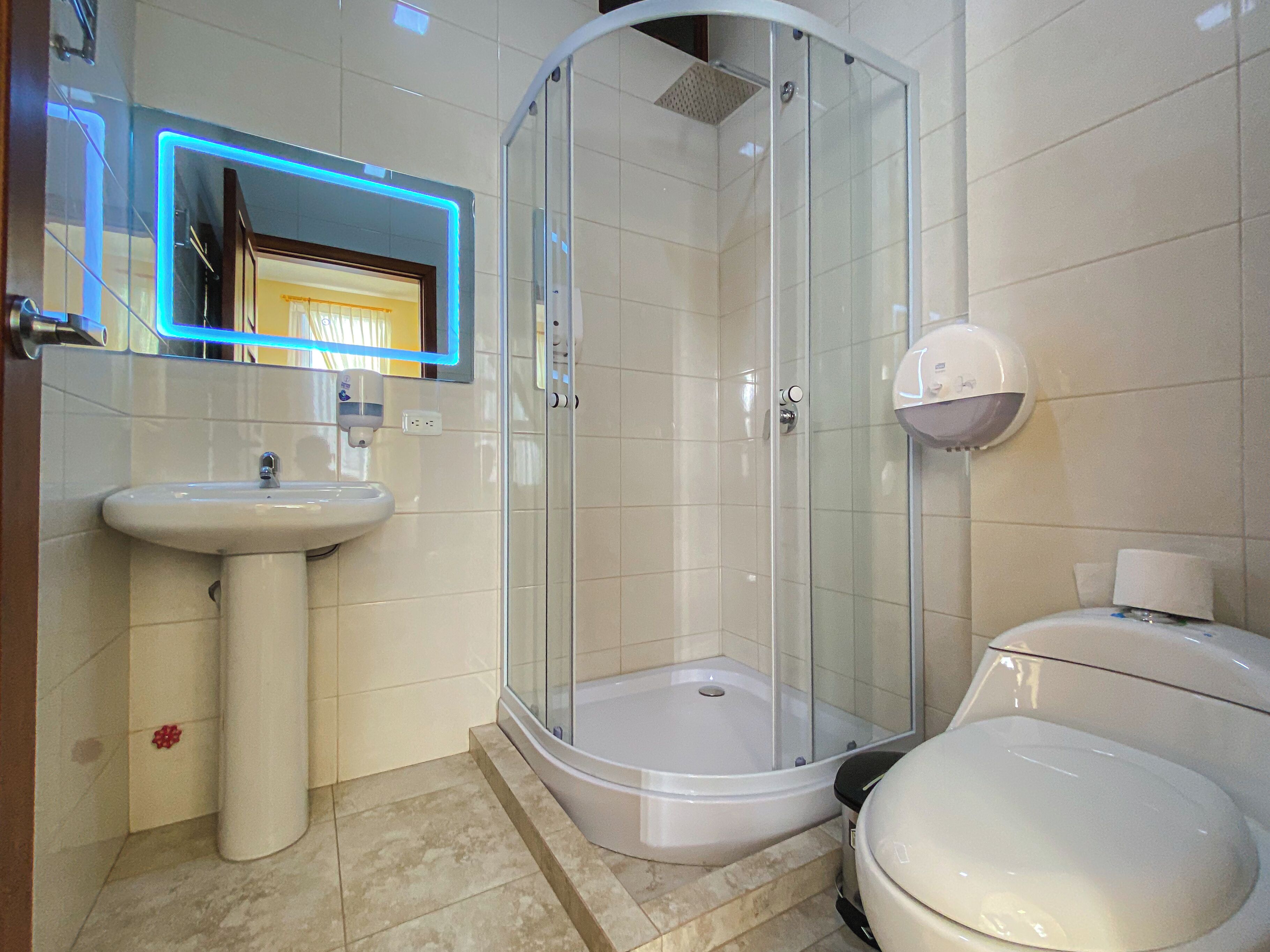 Une salle de bain moderne avec une douche à parois de verre, un lavabo sur colonne et des toilettes.