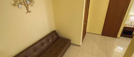 A hallway with a brown sofa, a decorative wall piece, and a wooden door.