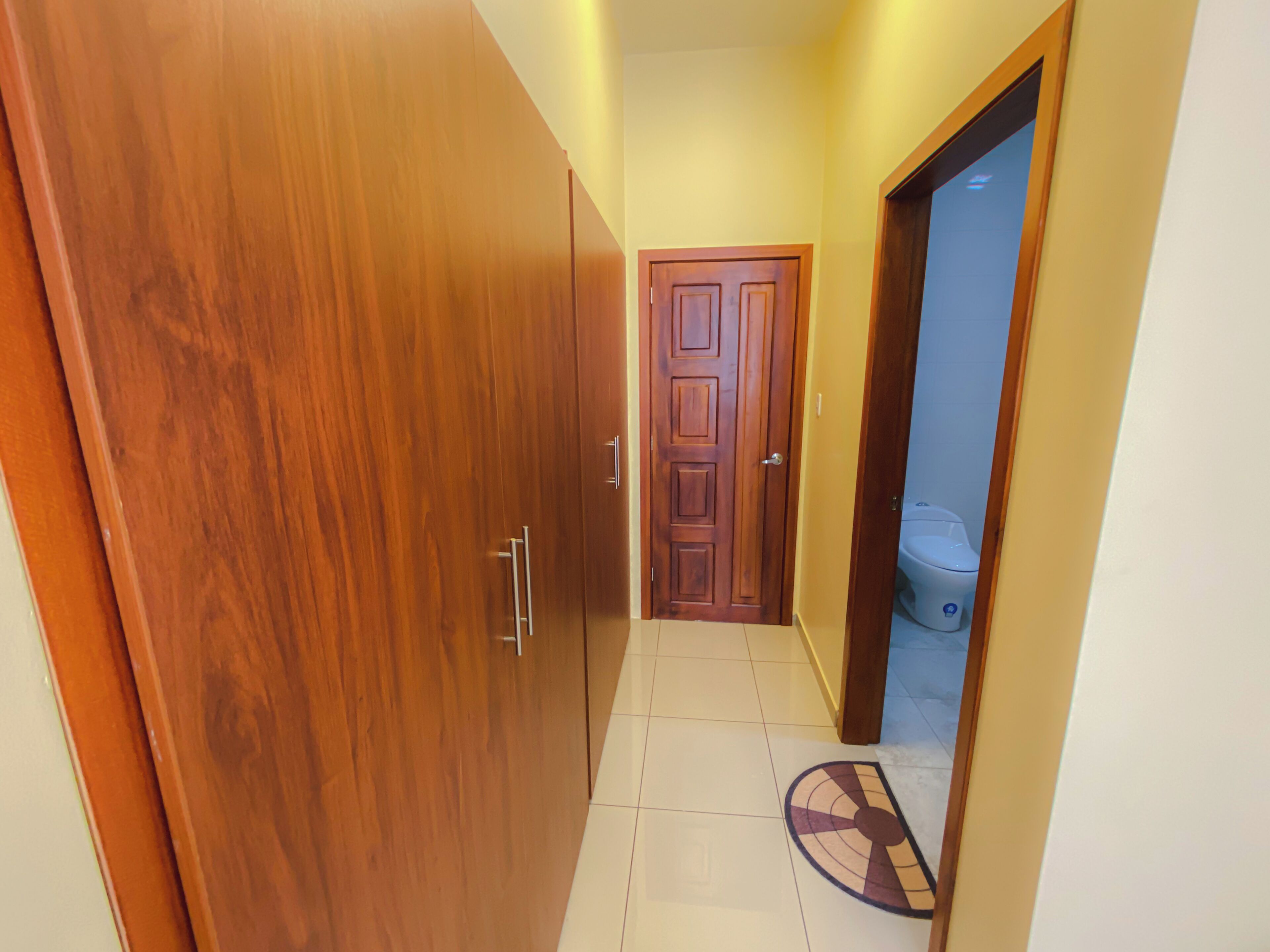 A hallway with wooden wardrobes and a door leading to a bathroom.