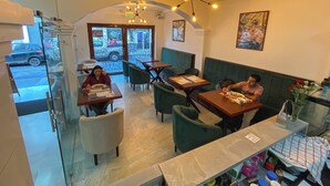 Un restaurant avec des tables et des chaises, une entrée avec une porte vitrée et un luminaire au plafond.
