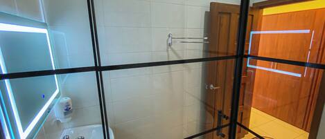 Une salle de bain avec une paroi en verre, un lavabo, un miroir et un espace douche.