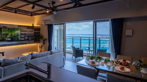 A modern living room with a sofa, dining table, and a view of the ocean.