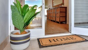 A modern entrance with a potted plant, a wicker storage unit, and a 'HOME' doormat. - Filoli - A breathtaking waterfront (Salamander Bay)