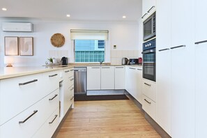 Una cucina moderna con mobili bianchi, elettrodomestici in acciaio inossidabile e pavimento in legno.