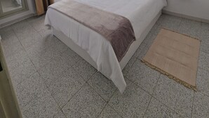 Un dormitorio con una cama grande, una mesita de noche, un espejo y una ventana con cortinas.