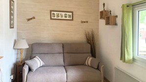 Una sala de estar con un sofá gris, una mesita de noche con una lámpara y un cuadro en la pared.