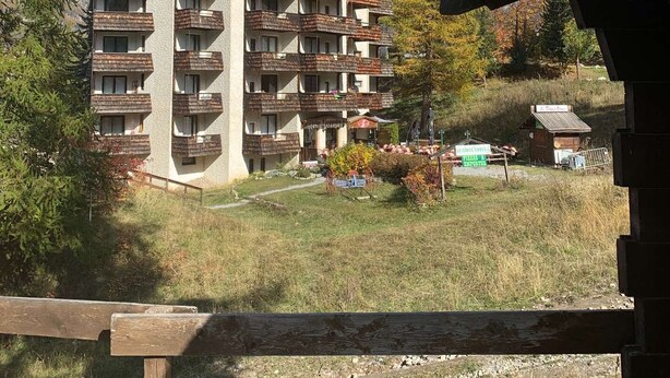 Un edificio de varios pisos con balcones, rodeado de árboles y una zona verde.