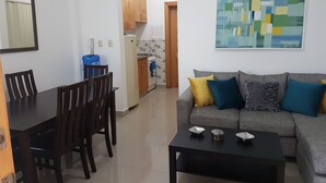 Una sala de estar moderna con un sofá gris, una mesa de centro negra y un comedor con una mesa y sillas de madera.