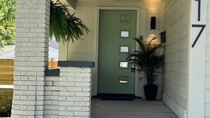 A house with a green door, a number 317 on the wall, and a covered porch with steps leading to the entrance. - The Hoosier House! An entire property experience! (Indianapolis)