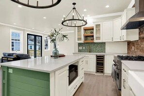 Una cocina moderna con armarios blancos, una isla grande, horno empotrado y estufa a gas.