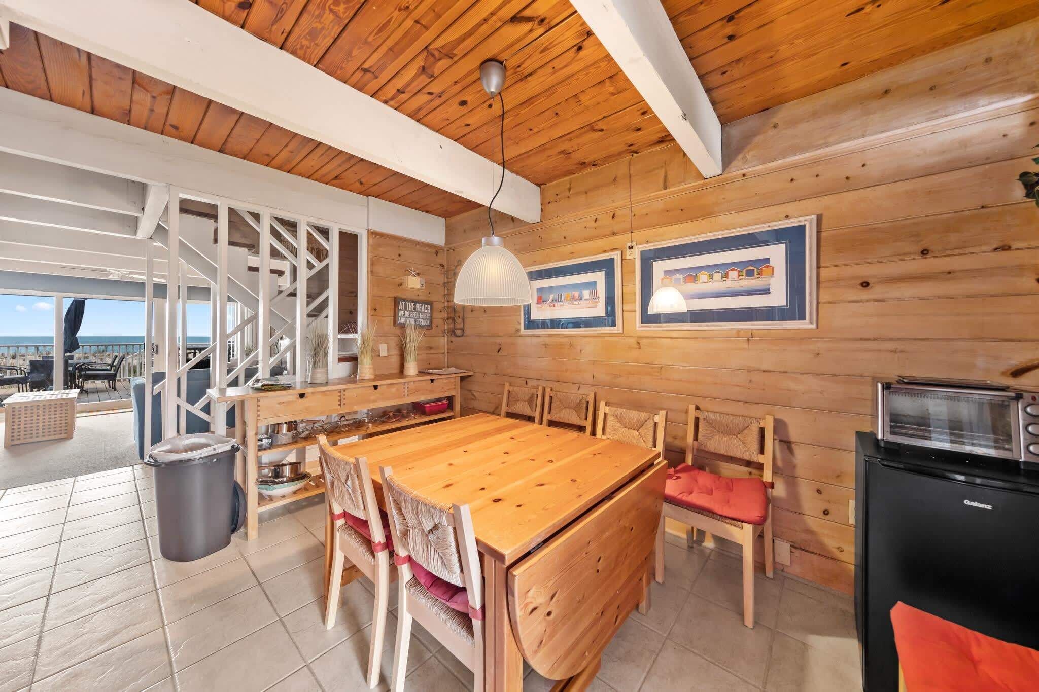 Un interior de madera con una mesa de comedor, sillas, una zona de cocina y vistas al exterior.