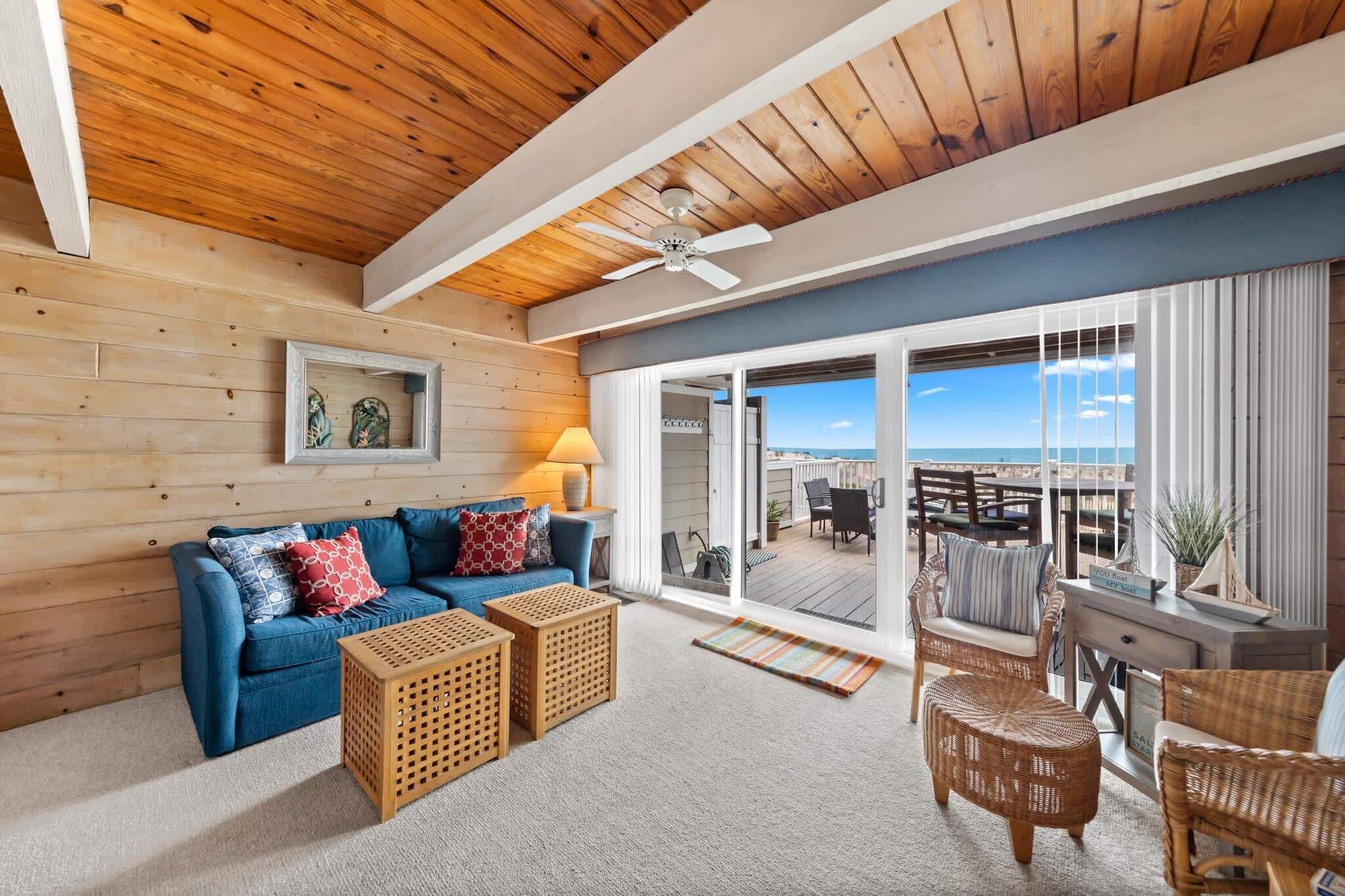 A modern living room with a blue sofa, wooden side tables, and a ceiling fan.