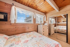 A wooden cabin bedroom with a bed, dresser, and a mirror.