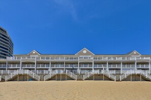 A beachfront hotel with multiple balconies and a sandy beach in front.