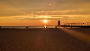 A beach scene with a sunset, a pier, and a lighthouse. - Perfect for Multiple Families- Close to Beach, Trails, Wineries, Breweries (South Haven)