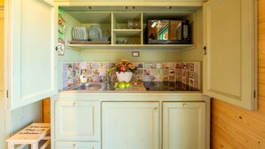 Una cocina compacta con microondas, repisas y salpicadero de azulejos.